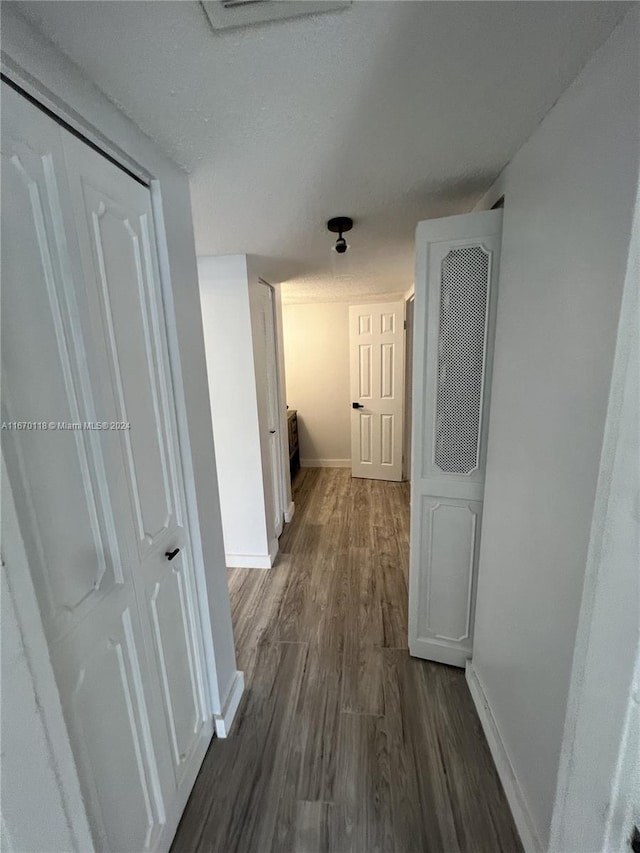 corridor featuring a textured ceiling and dark hardwood / wood-style floors