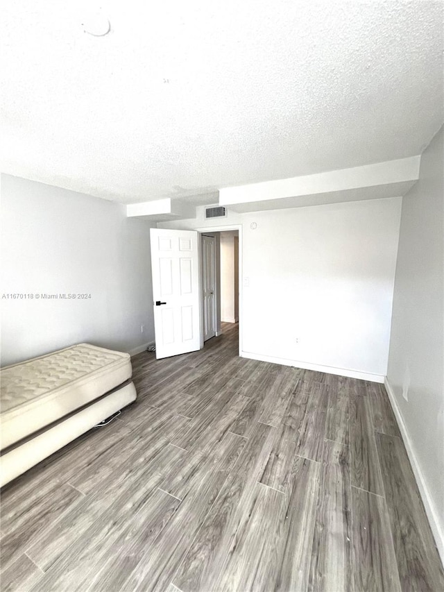 unfurnished bedroom with a textured ceiling and hardwood / wood-style floors