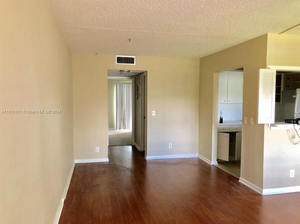 unfurnished room featuring a textured ceiling and dark hardwood / wood-style flooring