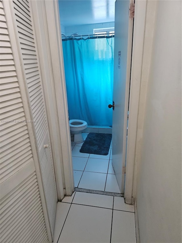 bathroom with tile patterned flooring, walk in shower, and toilet