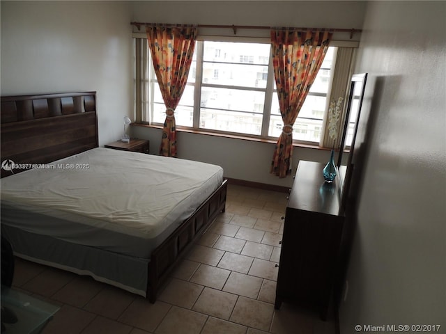 bedroom with multiple windows and tile patterned flooring