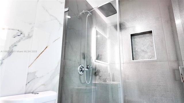 bathroom with a tile shower and toilet