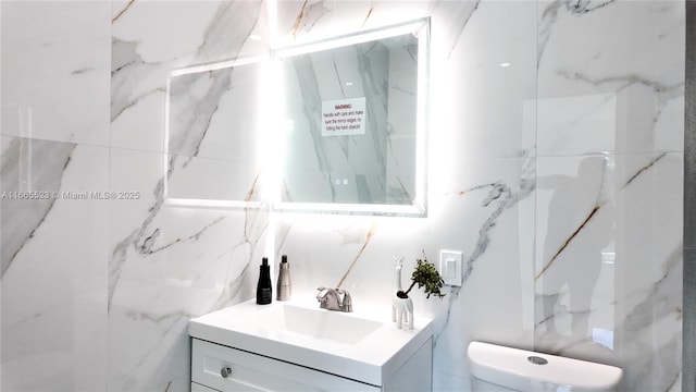 bathroom featuring vanity, tile walls, and toilet