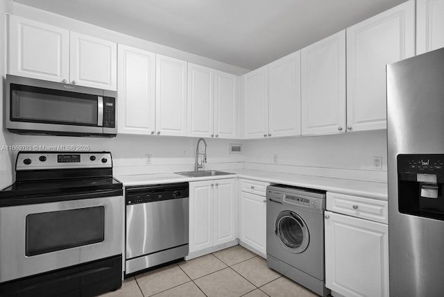 kitchen with washer / dryer, light tile patterned floors, stainless steel appliances, white cabinetry, and a sink