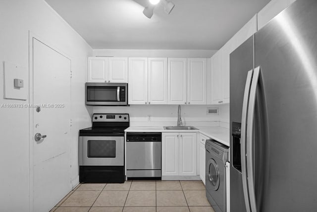 kitchen featuring light tile patterned floors, a sink, white cabinetry, appliances with stainless steel finishes, and washer / dryer