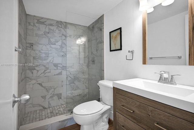 full bathroom with tiled shower, vanity, and toilet