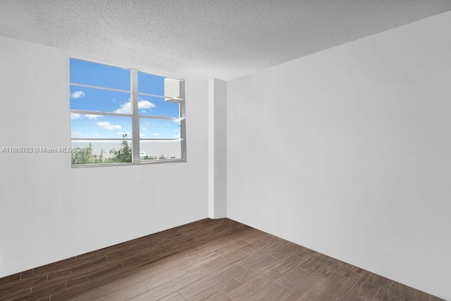 unfurnished room with a textured ceiling and wood finish floors