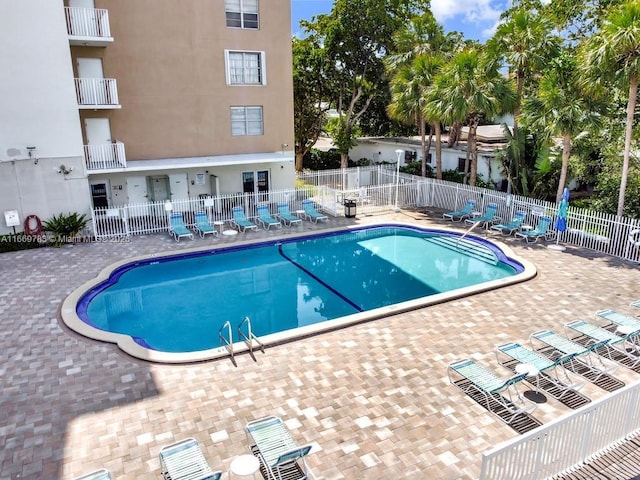 community pool with a patio area and fence