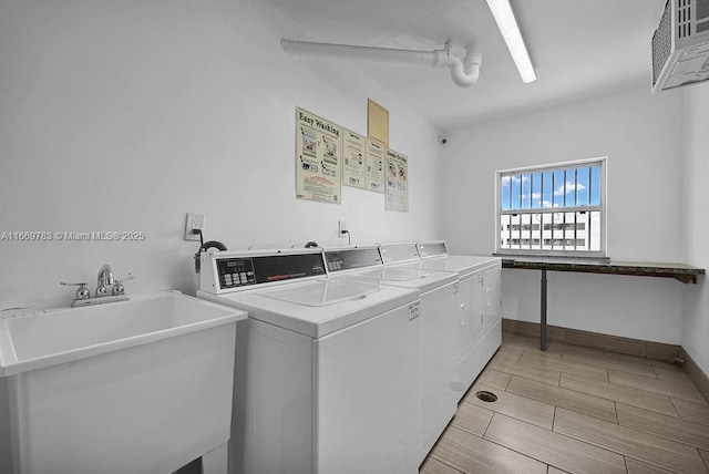 common laundry area featuring wood finish floors, independent washer and dryer, a sink, and baseboards