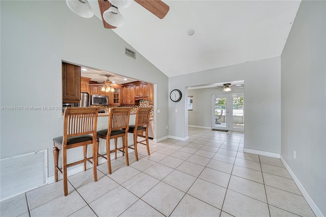 dining area featuring ceiling fan, light tile patterned floors, and high vaulted ceiling