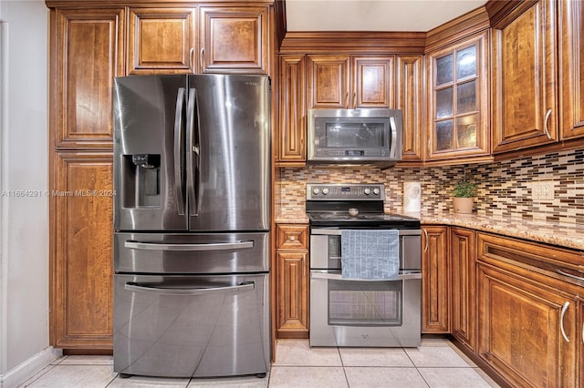 kitchen featuring light stone countertops, light tile patterned flooring, stainless steel appliances, and backsplash