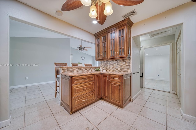 kitchen with backsplash, kitchen peninsula, light tile patterned flooring, and vaulted ceiling