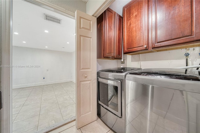 laundry area with cabinets, light tile patterned floors, and separate washer and dryer