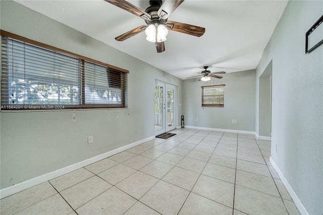 tiled empty room featuring ceiling fan and french doors