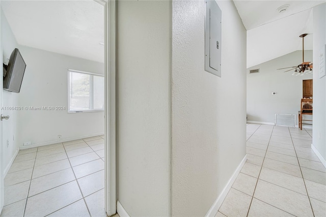 hallway featuring lofted ceiling, electric panel, and light tile patterned floors