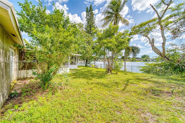 view of yard with a sunroom and a water view