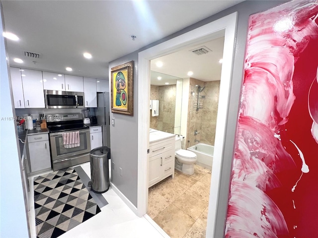 full bathroom with tiled shower / bath, vanity, tile patterned flooring, and toilet