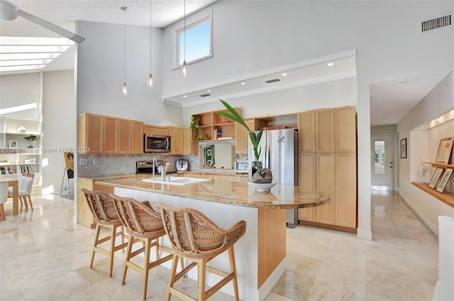 kitchen with a kitchen breakfast bar, hanging light fixtures, a towering ceiling, tasteful backsplash, and light stone countertops