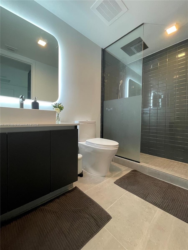 bathroom featuring a tile shower, vanity, toilet, and tile patterned floors