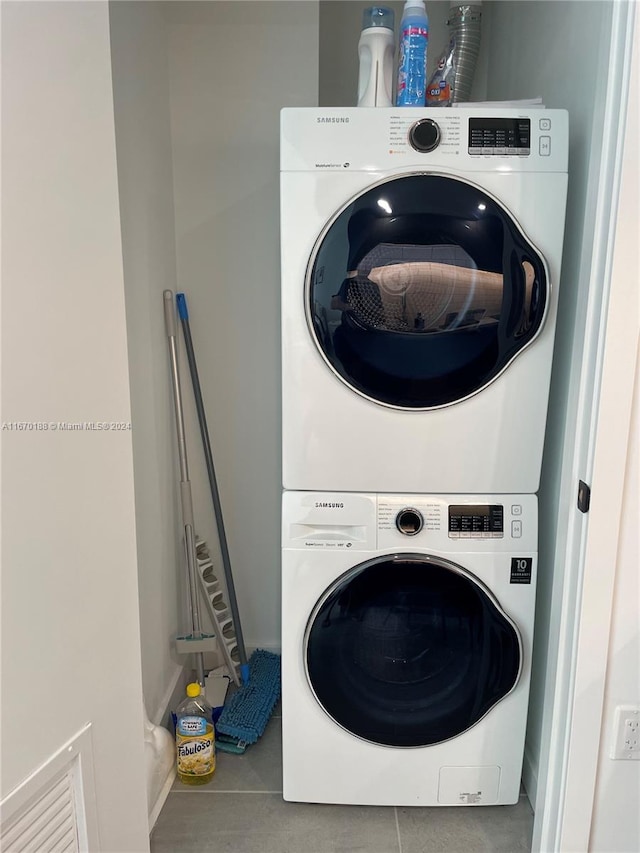 laundry room featuring tile patterned flooring and stacked washer and dryer