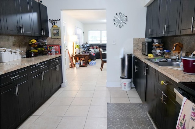 kitchen with backsplash, light tile patterned flooring, stove, and sink