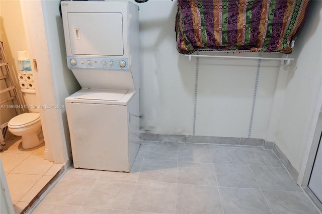 laundry room with stacked washer and clothes dryer and light tile patterned floors