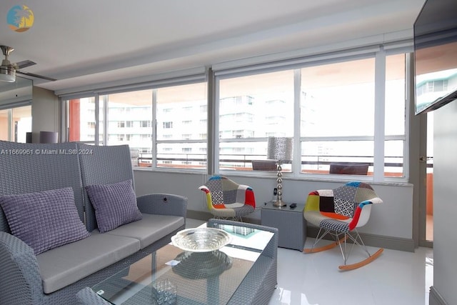 living room featuring finished concrete floors, baseboards, a wealth of natural light, and ceiling fan