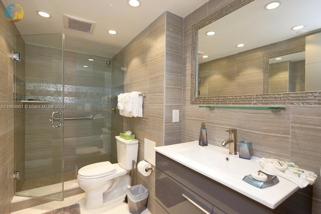 bathroom with tile walls, a shower with shower door, vanity, and toilet