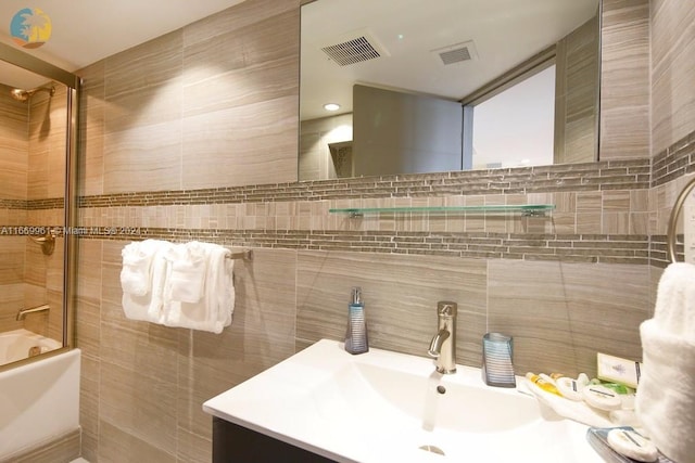 full bath featuring tile walls, visible vents, vanity, and  shower combination