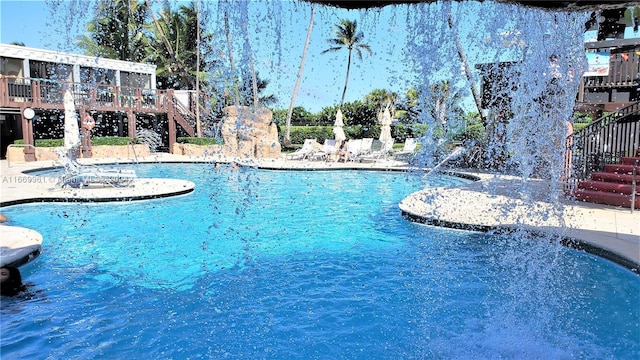 pool with a wooden deck, a patio area, and stairs