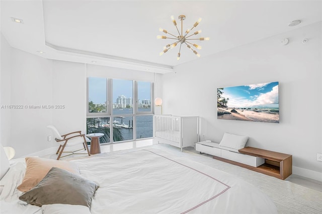 bedroom featuring a chandelier, a water view, and a raised ceiling