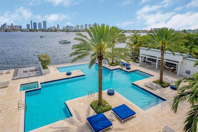 view of pool with a patio area, a water view, and a hot tub