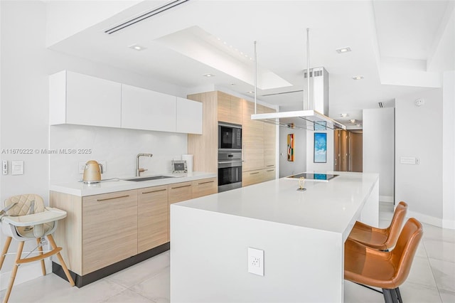 kitchen featuring white cabinetry, stainless steel oven, sink, a spacious island, and a breakfast bar area