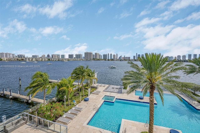 view of swimming pool featuring a patio area, a water view, and a boat dock