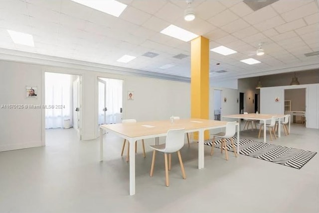 dining area with a paneled ceiling and concrete flooring