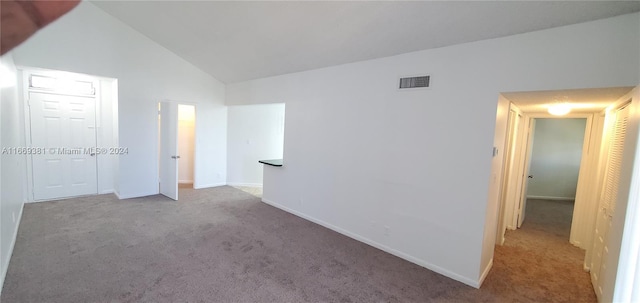 carpeted empty room with high vaulted ceiling