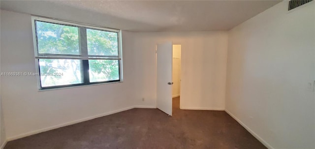 unfurnished room with dark colored carpet and plenty of natural light