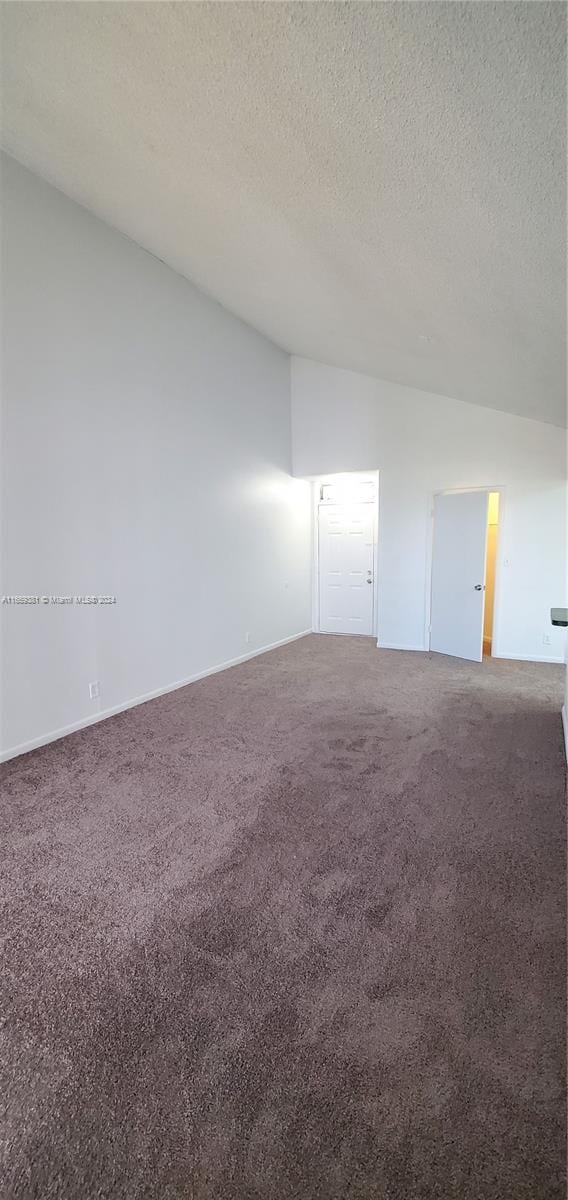 carpeted spare room featuring vaulted ceiling and a textured ceiling