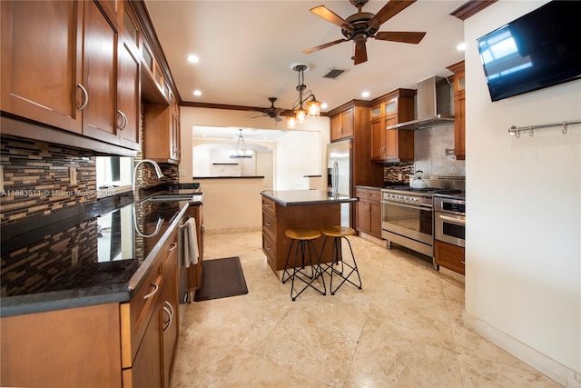 kitchen with wall chimney range hood, crown molding, a breakfast bar area, a kitchen island, and appliances with stainless steel finishes