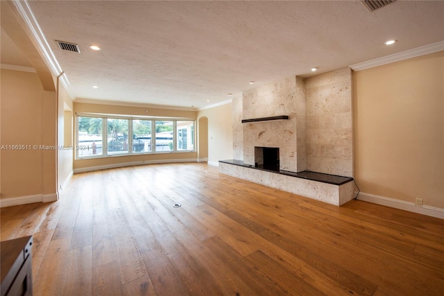 unfurnished living room featuring wood-type flooring, a textured ceiling, and crown molding