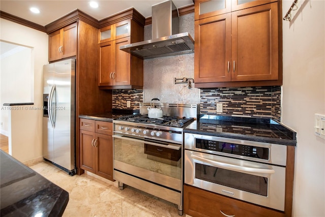 kitchen featuring wall chimney range hood, crown molding, dark stone countertops, stainless steel appliances, and backsplash