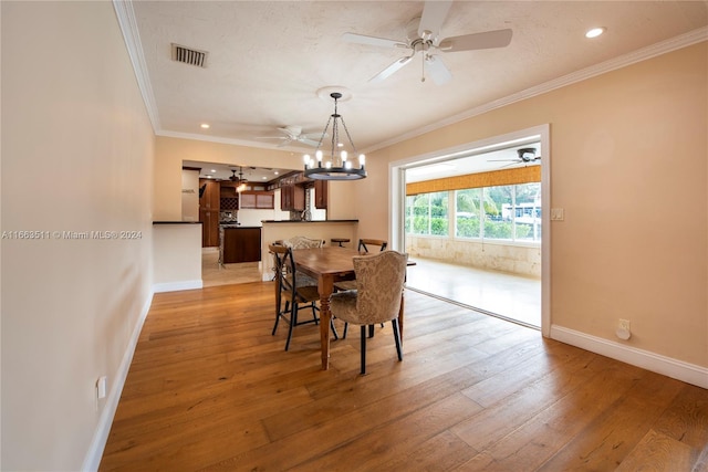 dining space with a notable chandelier, light wood-type flooring, and ornamental molding