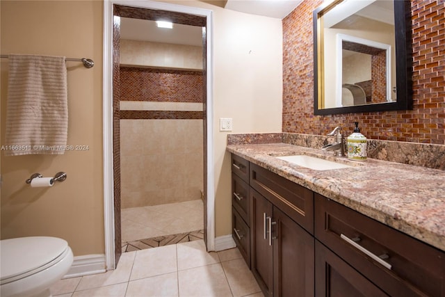 bathroom with toilet, tasteful backsplash, tile patterned floors, vanity, and tiled shower