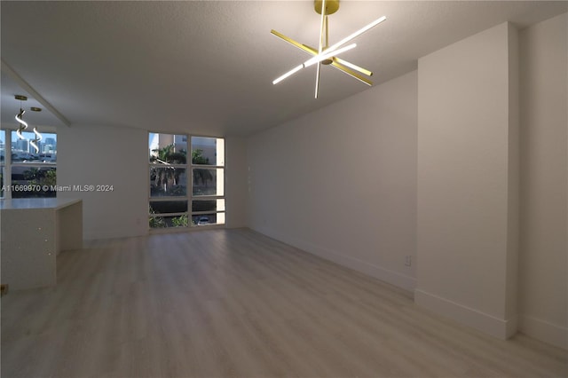 unfurnished room featuring a textured ceiling, wood-type flooring, and a chandelier