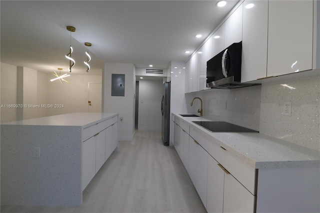 kitchen featuring light hardwood / wood-style floors, white cabinets, stainless steel refrigerator, pendant lighting, and black electric stovetop