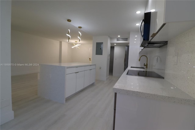 kitchen with black electric stovetop, light hardwood / wood-style floors, sink, white cabinetry, and hanging light fixtures