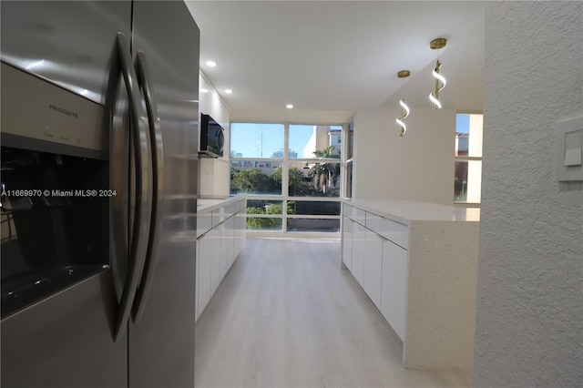 kitchen featuring stainless steel fridge, plenty of natural light, pendant lighting, and white cabinets