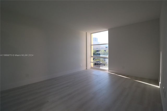 empty room featuring a wall of windows and dark hardwood / wood-style flooring