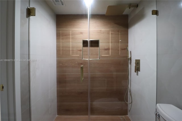 bathroom with a shower with door and toilet