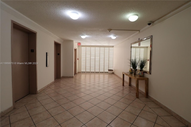 corridor featuring a textured ceiling, light tile patterned flooring, and elevator